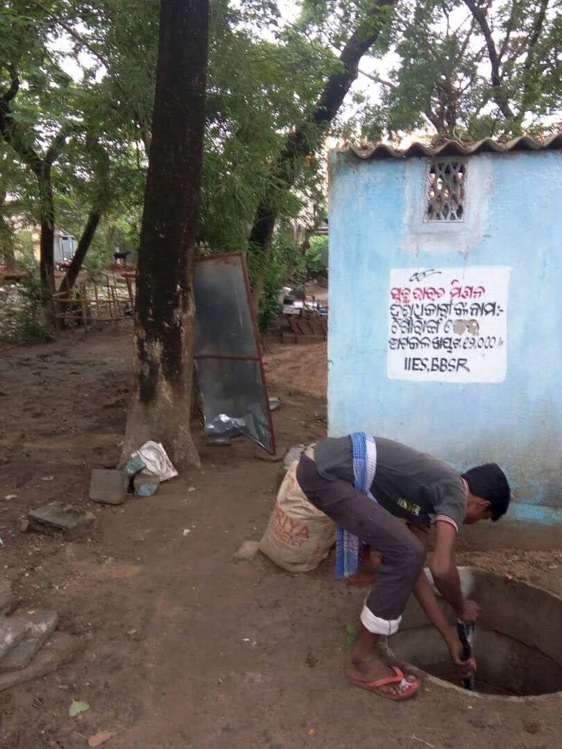 An IIES field worker preparing a twin-pit latrine at a household in a project village